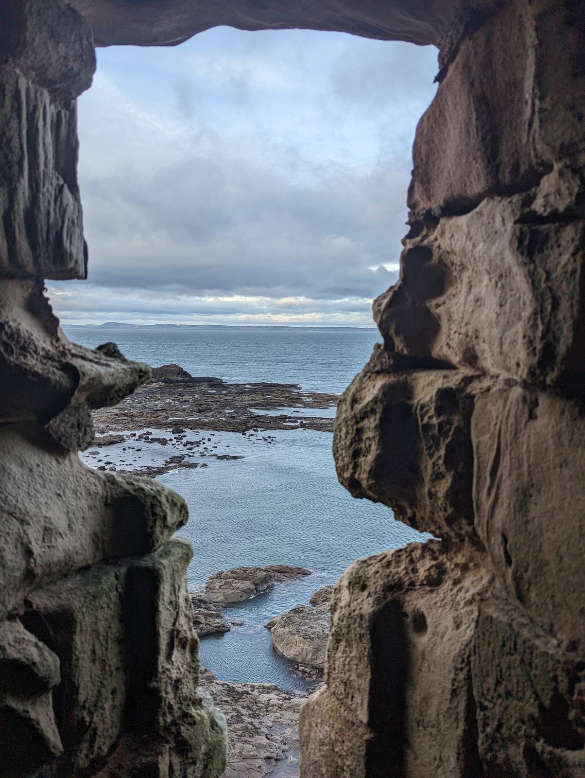 The sea cliffs on which Tantallon Castle stands, waves below.