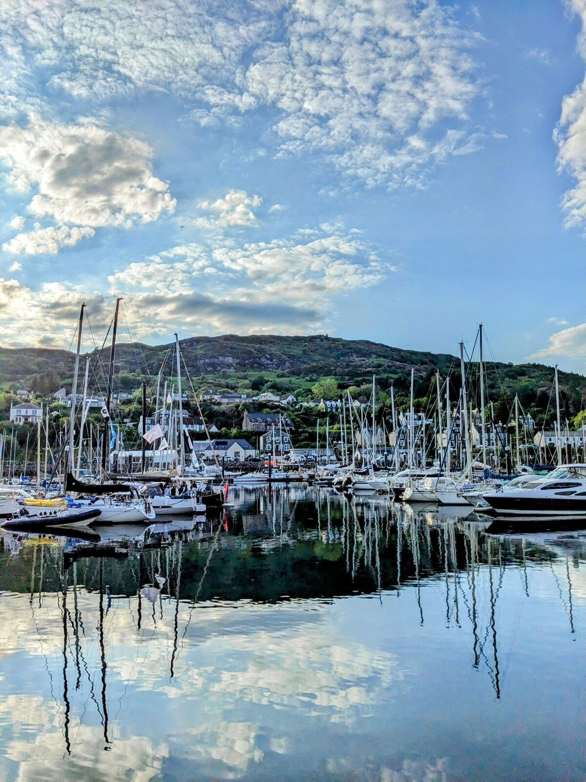 Still reflections of boats and hills on Loch Fyne at Tarbert at dusk.