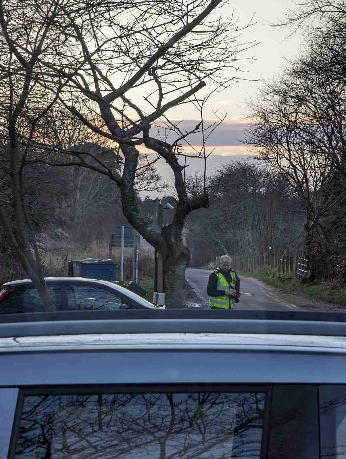 A parking warden in a hi-vis vest checking vehicles in the Tyninghame car park.
