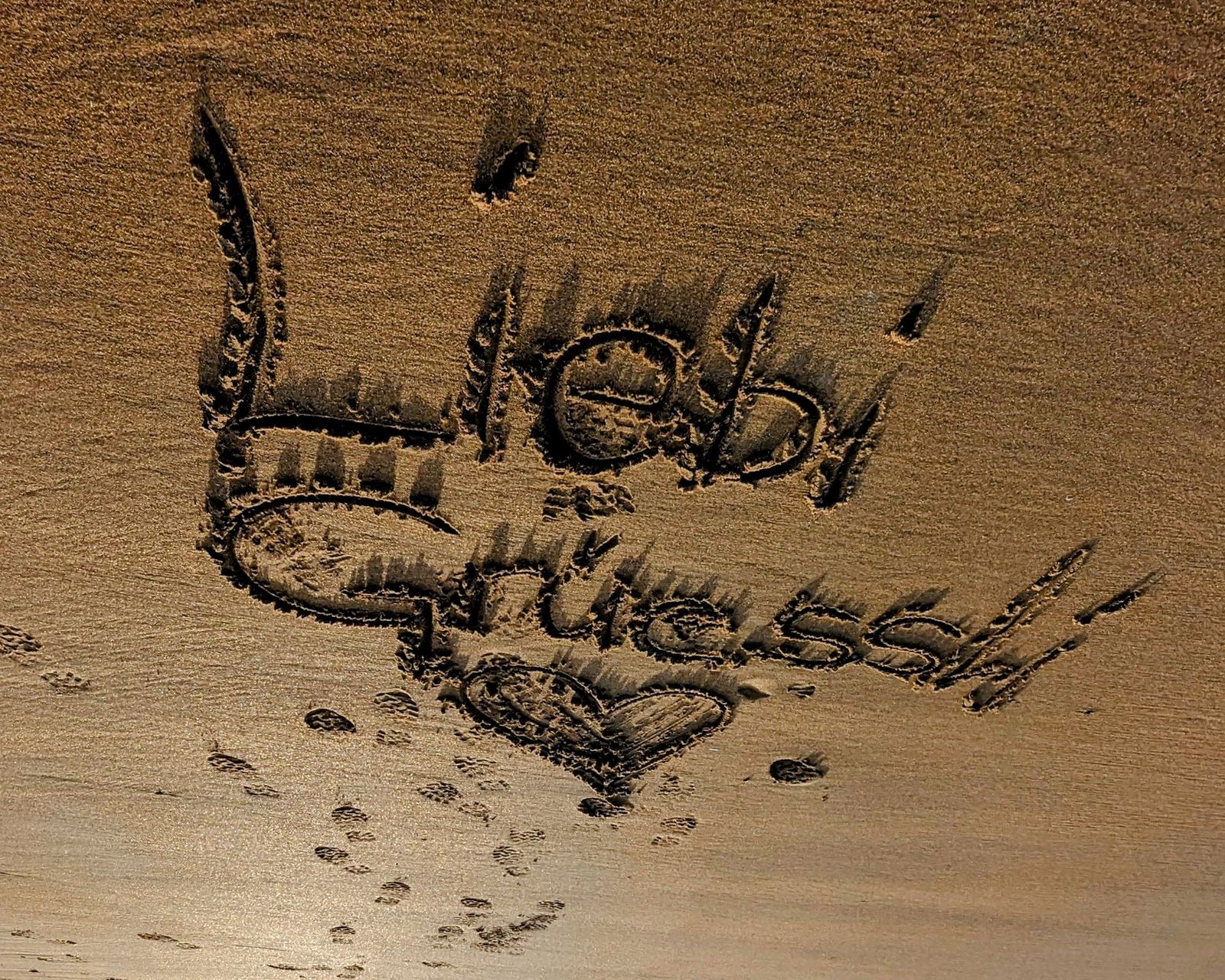 A greeting written in the sand on Tyninghame beach at low tide.