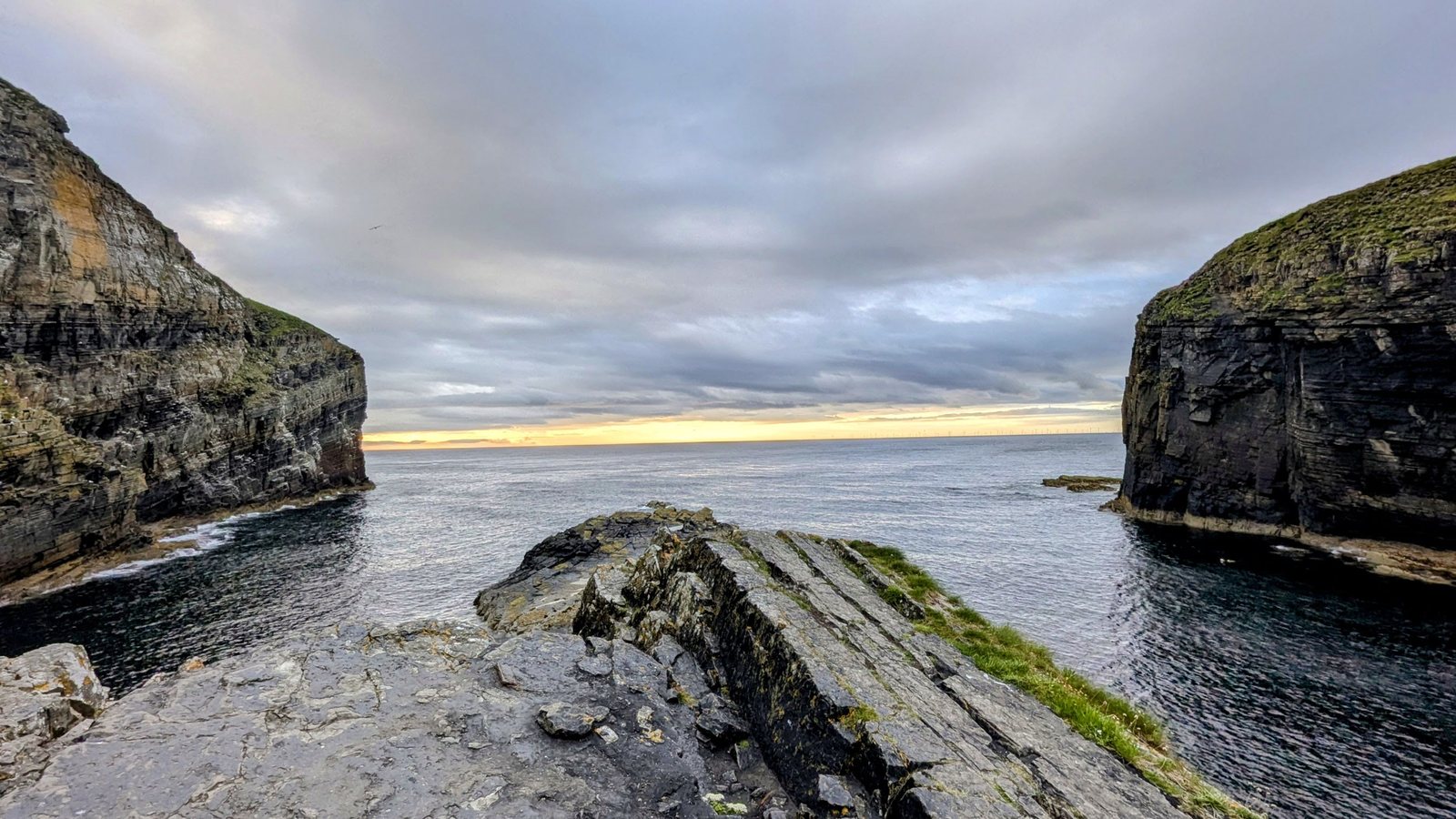 Layered rocky shore and cliffs at Whaligoe in evening light.